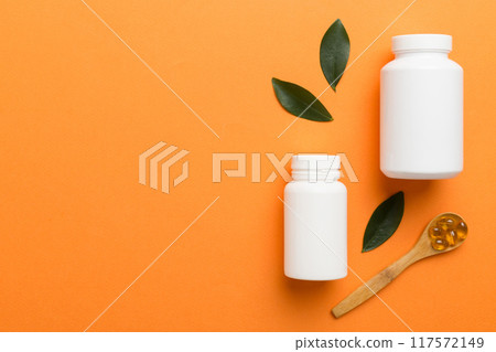 supplement pills with medicine bottle health care and medical top view. Vitamin tablets. Top view mockup bottle for pills and vitamins with green leaves, natural organic bio supplement, copy space 117572149