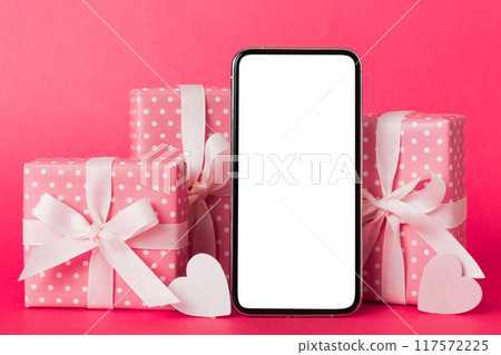 mobile phone with blank screen on colored background with hearts, calendar and gift box, valentine day concept perspertive view flat lay mobile phone with blank screen on colored background with hearts, calendar and gift box, valentine day concept perspertive view flat lay 117572225