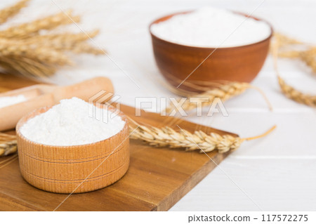 Flat lay of Wheat flour in wooden bowl with wheat spikelets on colored background. world wheat crisis 117572275