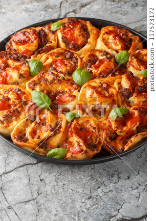 Italian pizza roll with tomatoes, cheese, sausages and basil close-up in baking dish. Vertical Italian pizza roll with tomatoes, cheese, sausages and basil close-up in baking dish. Vertical 117573172