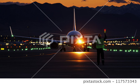 A ground crew guiding a large passenger aircraft into position on the runway using signals and hand gestures, 117573343