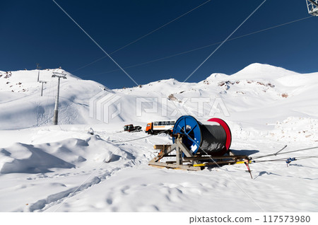 Power cable on reels. Thick electrical wire. Wire spools for outdoor use. Electrical products at a ski resort en street in the snow Power cable on reels. Thick electrical wire. Wire spools for outdoor use. Electrical products at a ski resort en street in the snow 117573980