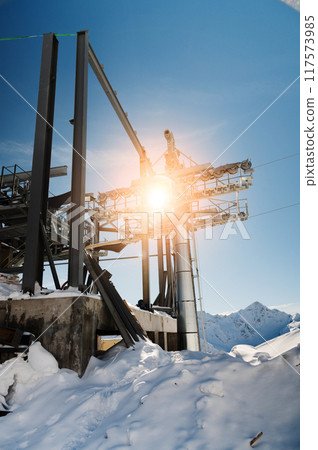 cable car towers, in the blue sky against the backdrop of snow-capped mountains. cable car construction, tourist resort 117573985