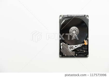 Disassembled hard drive on white background. Electronic insides of the storage device, reading head 117573996