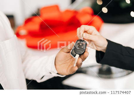 Close-up cropped shot of unrecognizable black male buyer getting car key and greetings from auto dealer while buying new auto in dealership. African car owner during handing over keys at auto showroom Close-up cropped shot of unrecognizable black male buyer getting car key and greetings from auto dealer while buying new auto in dealership. African car owner during handing over keys at auto showroom 117574407