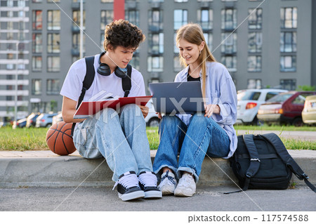 Teenage college students guy and girl talking, sitting outdoor Teenage college students guy and girl talking, sitting outdoor 117574588