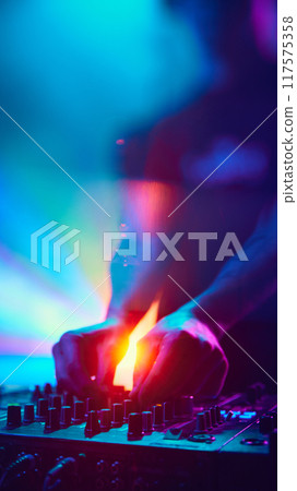 DJ, surrounded by swirling lights, mixes hypnotic set, his figure nearly merging with vibrant hues that fill air. 117575358