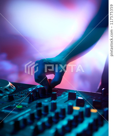 DJ immersed in music, his focus intense as vibrant colors surround him, blending sound and light into unforgettable experience. DJ immersed in music, his focus intense as vibrant colors surround him, blending sound and light into unforgettable experience. 117575359