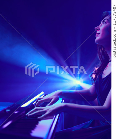 Lone pianist, illuminated by burst of spotlight, creates symphony that echoes beauty and intensity of colors surrounding her. 117575407
