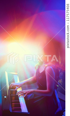 Surrounded by spectrum of radiant colors, vibrant stage lights, pianist loses herself in music. Instrumental performance. 117575408