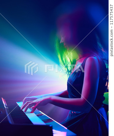 Side view photo of young woman, musician playing piano and singing. Stage performance. Festival of instrumental music. 117575437
