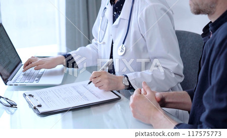 Doctor and patient are talking in clinic after usual health check up. Female physician is making notes and using laptop computer. Medicine concept Doctor and patient are talking in clinic after usual health check up. Female physician is making notes and using laptop computer. Medicine concept 117575773