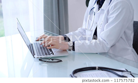 Doctor woman is sitting and typing on laptop computer, hands close up. Medicine and healthcare concept 117575782