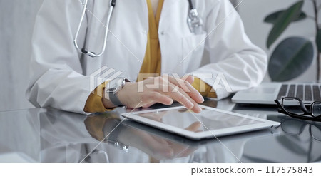 Doctor woman using tablet on the glass desk in medical office. Medicine and health care Doctor woman using tablet on the glass desk in medical office. Medicine and health care 117575843
