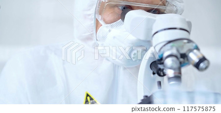 Professional scientist in protective gear is using microscope in a laboratory setting, close-up. Science and medicine concepts 117575875