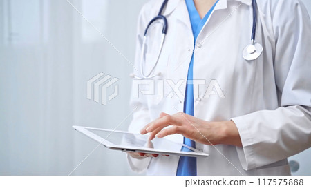 Doctor woman is using digital tablet in clinic. Healthcare professional with a stethoscope operating a touch screen tablet computer while standing straight. Medicine concept Doctor woman is using digital tablet in clinic. Healthcare professional with a stethoscope operating a touch screen tablet computer while standing straight. Medicine concept 117575888
