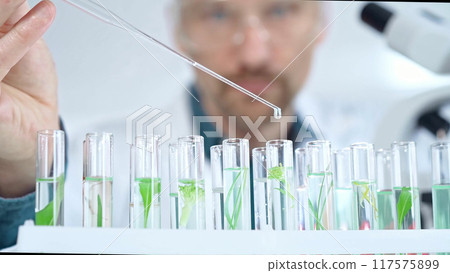 Man researcher with safety glasses is working with lab tubes using a pipette in laboratory, close-up of lab equipment. Science and medicine 117575899