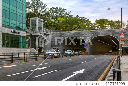 Yulgok Tunnel near Changgyeonggung Palace, flanked by a building with a coffee shop. Vehicles are driving toward the tunnel entrance. 117575909