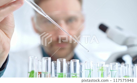 Man researcher with safety glasses is working with lab tubes using a pipette in laboratory, close-up of lab equipment. Science and medicine Man researcher with safety glasses is working with lab tubes using a pipette in laboratory, close-up of lab equipment. Science and medicine 117575948