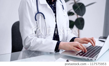 Doctor woman is using laptop computer at glass table in clinic. Medicine and pharmacy concept Doctor woman is using laptop computer at glass table in clinic. Medicine and pharmacy concept 117575953