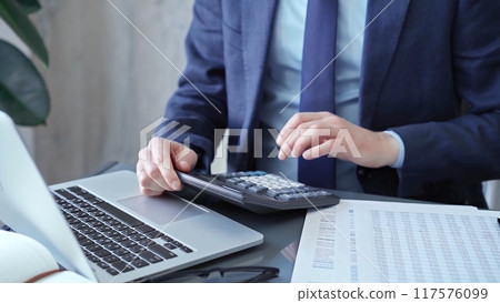 Businessman analyzing financial data on laptop and calculator. Close-up of a professional auditor working on financial reports. Business concept 117576099