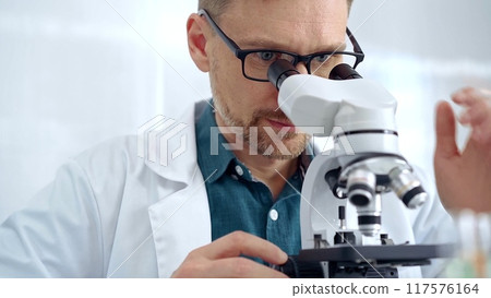 Man scientist with protective glasses using microscope in laboratory. Microbiology science concept Man scientist with protective glasses using microscope in laboratory. Microbiology science concept 117576164