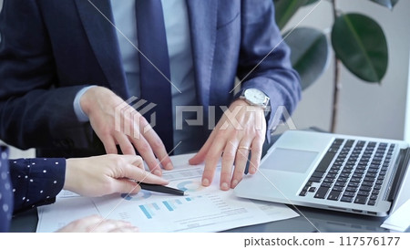 Two professionals analyzing a pie chart during a strategic business meeting. Business meeting with graph analysis Two professionals analyzing a pie chart during a strategic business meeting. Business meeting with graph analysis 117576177