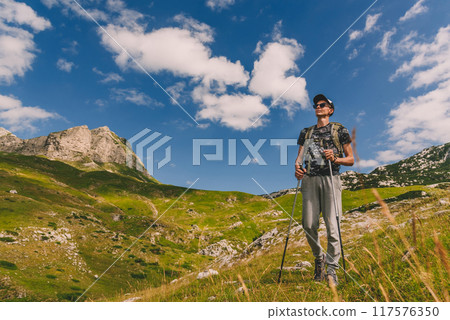 Man Walking with Hiking Poles on Mountains 117576350