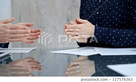 Unrecognizable business people shaking hands and clapping over glass table after contract signing in office. Agreement and handshake themes 117576363