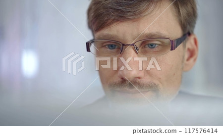 Businessman with glasses looking intently obscured partially by a translucent surface of laptop. Business people concept Businessman with glasses looking intently obscured partially by a translucent surface of laptop. Business people concept 117576414