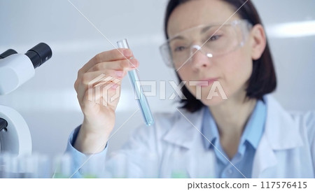 Scientist female researcher with protective glasses examining la 117576415