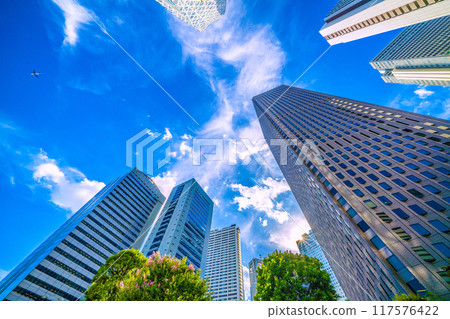 Tokyo cityscape in Japan: An airplane passes over Shinjuku...Tokyo Metropolitan Government Building in the background. Inbound tourism revives, a ray of hope for a new era = August 20th 117576422