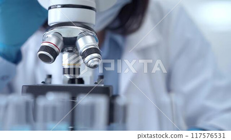 Scientist using microscope in laboratory. Close-up of a researcher's hands adjusting a modern microscope in a lab setting 117576531