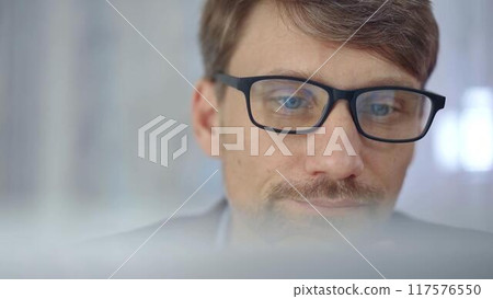 Businessman with glasses looking intently obscured partially by a translucent surface of laptop. Business concept 117576550