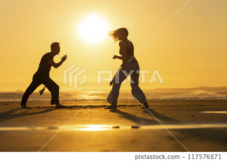 Couple practicing capoeira martial art on the beach at sunset 117576871