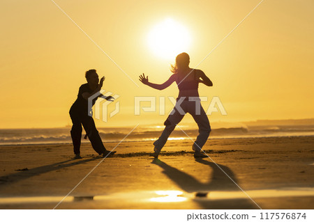 Couple practicing capoeira martial art at sunset on the beach 117576874
