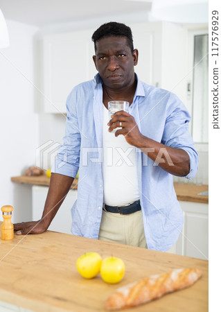 Man holding glass, drinking water at home 117576929