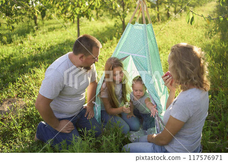 family with toddler playing in wigwam in garden 117576971