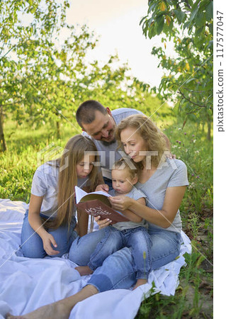 family reading the holy bible on a picnic in the garden family reading the holy bible on a picnic in the garden 117577047