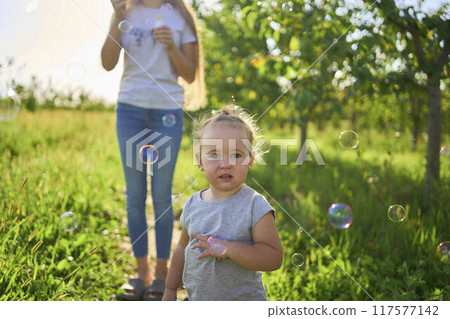 teen sister blowing soap bubbles for toddler 117577142
