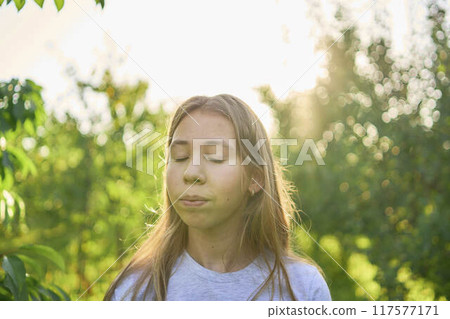 a portrait of a teenage girl with long blond hair in a sunlit garden 117577171