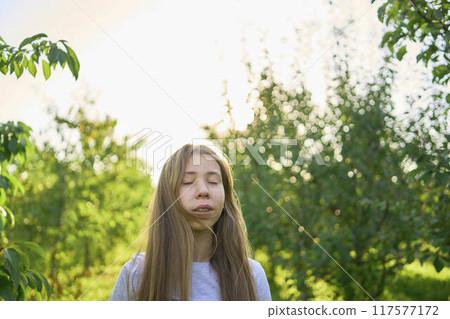a portrait of a teenage girl with long blond hair in a sunlit garden 117577172