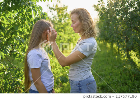 mother and teenage girls with long blond hair spend time together in the sunlit park mother and teenage girls with long blond hair spend time together in the sunlit park 117577190