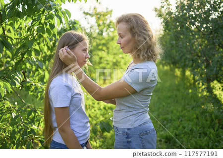 mother and teenage girls with long blond hair spend time together in the sunlit park mother and teenage girls with long blond hair spend time together in the sunlit park 117577191