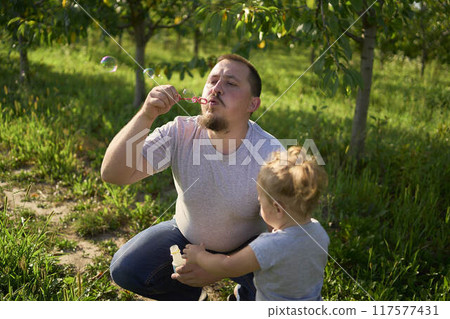 a family of four is playing catch bubbles in the garden a family of four is playing catch bubbles in the garden 117577431
