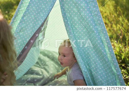 family with toddler playing in wigwam in garden 117577674