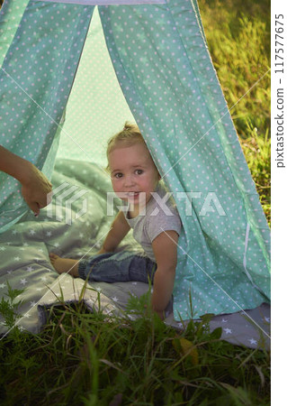 family with toddler playing in wigwam in garden 117577675