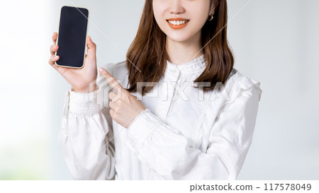 A smiling Japanese business woman pointing at a smartphone 117578049