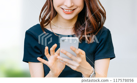 使用智慧型手機的微笑的日本女商人 使用智慧型手機的微笑的日本女商人 117578056