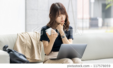 A Japanese businesswoman thinking while using a computer and smartphone A Japanese businesswoman thinking while using a computer and smartphone 117578059